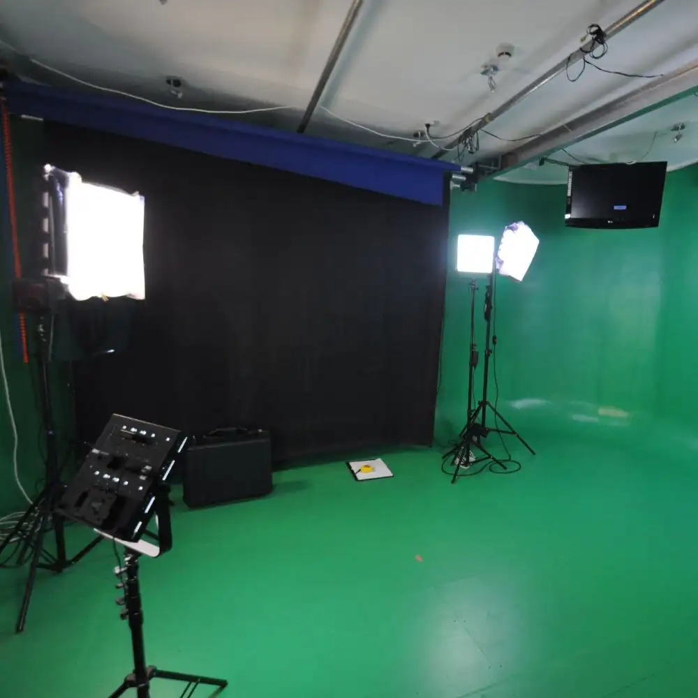 Photo of a studio with green walls, bright lights, and a black backdrop.