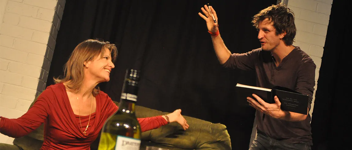A photo of a woman and a man engaging in conversation on a stage setting.