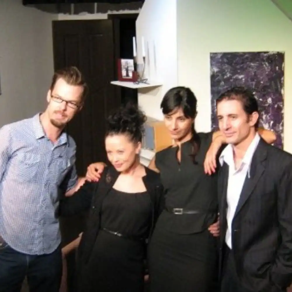Four people standing together indoors, posing for a group photo.