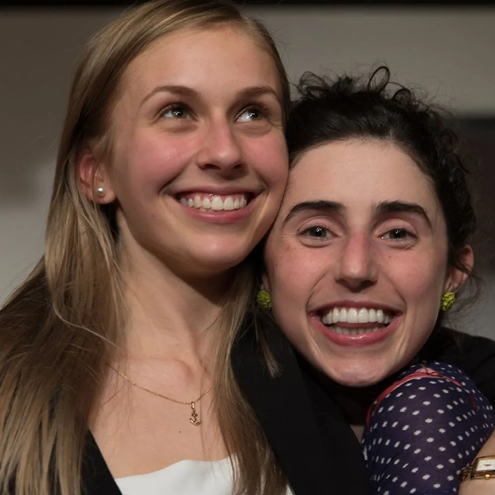 Two people smiling, facing forward. Upper body portrait, close-up.