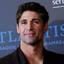 Portrait of a man with short dark hair and a slight smile wearing a black jacket at an event.