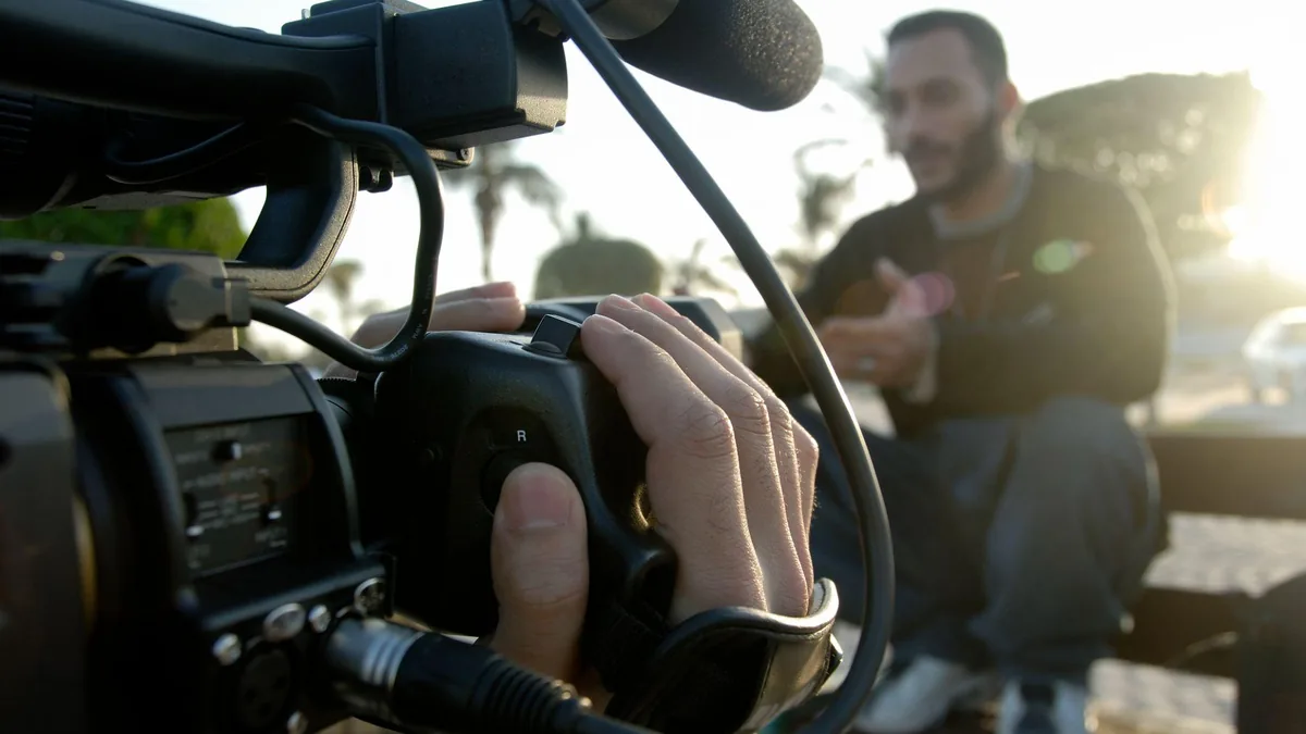 Close-up of a video camera filming a person outdoors